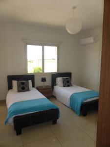 een slaapkamer met 2 bedden en een raam bij Aphrodite Sands Resort complex has a sauna, fitness room, health spa, jacuzzis in Mandria