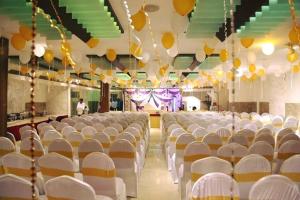 an empty hall with white chairs and yellow balloons at Hotel Kosala Vijayawada in Vijayawāda