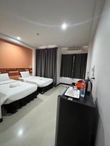 Habitación de hotel con 2 camas y escritorio en โรงแรมช้างใหญ่ใจดี, en Yasothon