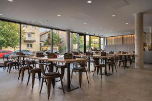 un restaurante con mesas y sillas de madera y ventanas en the niu Timber en Esslingen