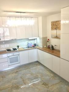 cocina con armarios blancos y suelo de mármol en 4-room jacuzzi apartment, en Leópolis