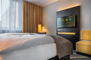 um quarto de hotel com uma cama e uma televisão de ecrã plano em the niu Fury em Aschheim