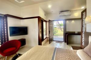 a bedroom with a bed and a chair and a television at Willo Stays Sea View Home Kannur Landsend in Kannur