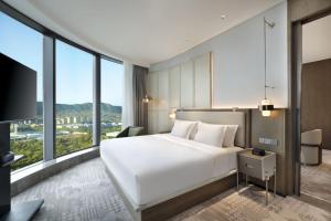 a bedroom with a large white bed and large windows at The Barony Jinan East in Jinan