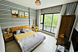 een slaapkamer met een bed en een groot raam bij The Grandparents Homestay in Quy Nhon
