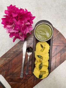 a plate of food with a bowl of sauce and flowers at AnandMai - Sustainable Living Spaces in Jaipur