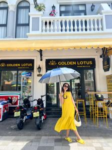 Una donna con un vestito giallo che tiene un ombrello di Golden Lotus Homestay a Phu Quoc