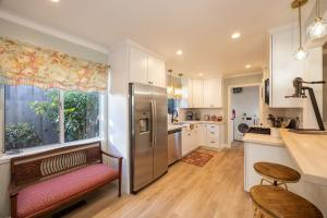 a kitchen with a stainless steel refrigerator and a window at Charming Garden Cottage- steps to historic Old Town Half Moon Bay in Half Moon Bay