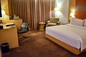 um quarto de hotel com uma cama e uma cadeira em All Sedayu Hotel Kelapa Gading em Jacarta