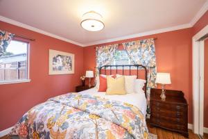 a bedroom with a bed with orange walls and a window at Charming Garden Cottage- steps to historic Old Town Half Moon Bay in Half Moon Bay