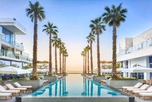 an image of a resort pool with palm trees at Lavish Sea View 2BR with M at Five Palm in Dubai