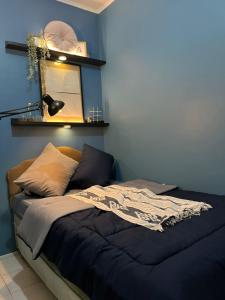 een bed in een slaapkamer met een blauwe muur bij Minyo Guest House in Jakarta