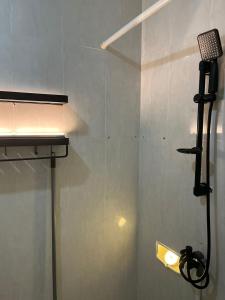 een douche met een glazen deur met een licht erop bij Minyo Guest House in Jakarta