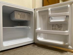 an empty refrigerator with its door open in a room at プチバスケット in Chiba