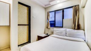 a bedroom with a bed and a window at Hotel Raj Inn in Navi Mumbai