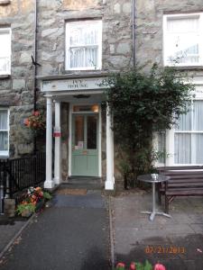 a stone building with a green door and a bench at Ivy House B&B in Dolgellau