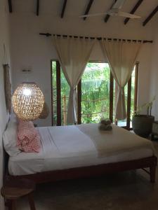 um quarto com uma cama com um candeeiro e uma janela em Maria Bonita Sri Lanka em Ahangama