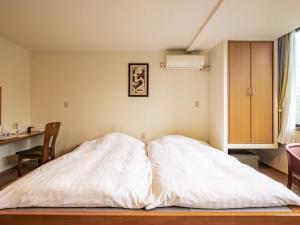 an unmade bed in a room with a kitchen at HAKONE GORA ONSEN Hotel Kasansui in Hakone