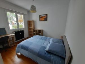 sypialnia z niebieskim łóżkiem i biurkiem w obiekcie Loft 4/6 pers proximité centre ville, gare et tram w Caen