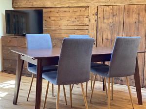 einem Holztisch mit vier Stühlen und einem TV in der Unterkunft Chalet Brünig in Meiringen