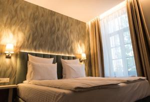 a bedroom with a bed with white pillows and a window at JOYME Hotel in Sibiu