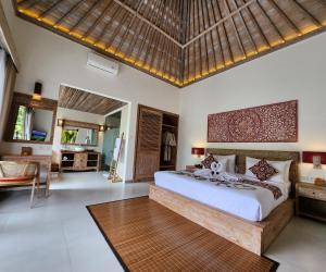 a bedroom with a large bed and a living room at Pinggala Villa Ubud in Gianyar