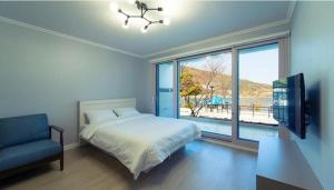 a bedroom with a bed and a large window at Seolli Resort Pension in Namhae