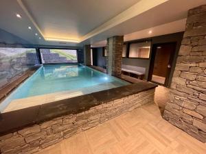una piscina en una casa con una pared de piedra en Suite Yellowstone en Peisey-Nancroix