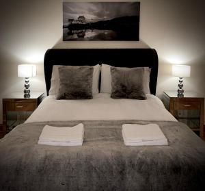 a bedroom with a bed with two tables and two towels at Lomond Castle Penthouse in Luss