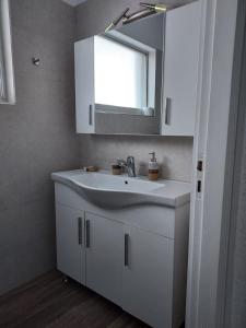 La salle de bains est pourvue d'un lavabo blanc et d'un miroir. dans l'établissement Aqua Apartments, à Loutra Elenis