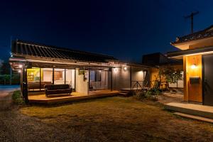 una casa con un banco en un porche por la noche en 深々 books&stay シンシンブックスアンドステイ en Matsukawa
