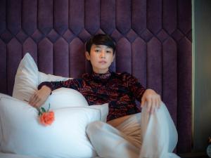 a young man sitting in a bed with pillows at MUU Bangkok Hotel in Bangkok