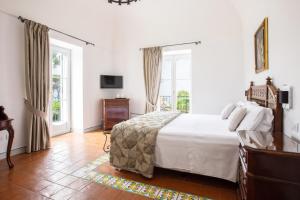 1 dormitorio con 1 cama blanca grande y ventanas en Oasi Olimpia Relais en SantʼAgata sui Due Golfi