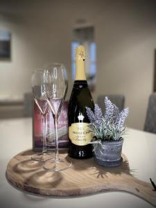 eine Flasche Wein und zwei Gläser auf einem Holztablett in der Unterkunft Lomond Castle Penthouse in Luss