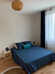 um quarto com uma cama azul e uma janela em Villa au calme dans un écrin de verdure em Aytré