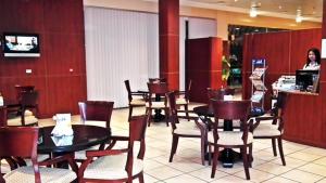 a restaurant with tables and chairs and a woman at a counter at Al Massa Hotel Apartments 1 in Al Ain