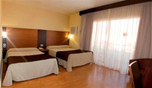 a hotel room with two beds and a window at Rincón Sol in Rincón de la Victoria