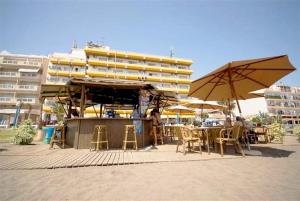 a cafe with tables and chairs and umbrellas on the beach at Rincón Sol in Rincón de la Victoria