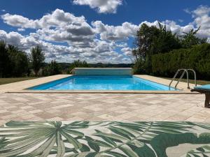 a large swimming pool in a yard with a sky at Le Gîte du Souffle des Anges in Sauveterre