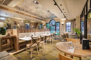a restaurant with wooden tables and chairs and windows at The Wynnstay Hotel, Oswestry, Shropshire - The Coaching Inn Group in Oswestry