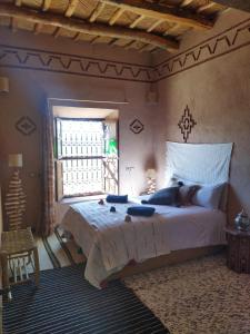 um quarto com uma cama grande e uma janela em Maison d'hôtes IZZA em El Kelaa des Mgouna