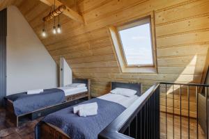 two beds in a wooden room with a window at Wierch Głodowski 25B by Homeprime in Bukowina Tatrzańska