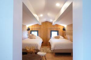 - 2 lits dans une chambre dotée de murs en bois dans l'établissement L'Etincelle Mountain Lodge, à Chamrousse