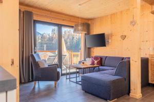 a living room with a couch and chairs and a television at Bergeralm Chalets by ALPS RESORTS in Steinach am Brenner