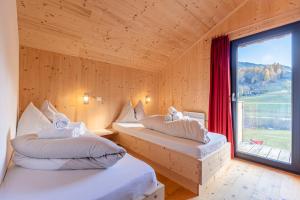 two beds in a room with a large window at Bergeralm Chalets by ALPS RESORTS in Steinach am Brenner