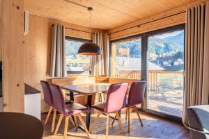 a dining room with a table and chairs and a large window at Bergeralm Chalets by ALPS RESORTS in Steinach am Brenner