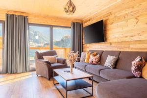 a living room with a couch and a tv at Bergeralm Chalets by ALPS RESORTS in Steinach am Brenner