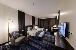 Habitación de hotel con 2 camas y TV en Lily Hotel Suite Hofuf, en Al Hofuf