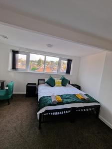 1 dormitorio con 1 cama con almohadas verdes y amarillas en Balco Sherwood House - 2 Bedrooms, 5 beds - Sky tv and internet en Nottingham