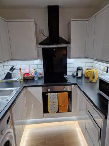 cocina con armarios blancos y fogones en Balco Sherwood House - 2 Bedrooms, 5 beds - Sky tv and internet en Nottingham
